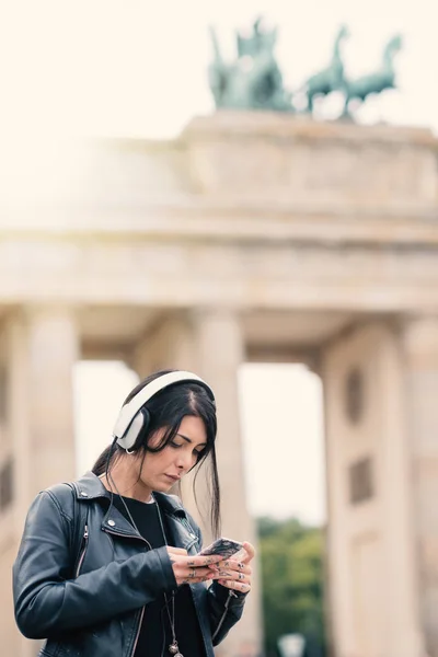 Giovane donna bruna con cuffie a Berlino. Porta di Brandeburgo — Foto Stock