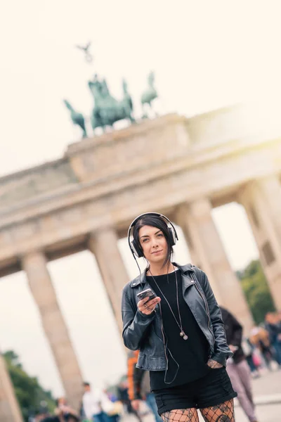 Giovane donna bruna con cuffie a Berlino. Porta di Brandeburgo — Foto Stock