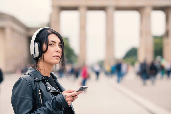 Young brunette woman with headphones in Berlin. Brandenburg Gate — ストック写真