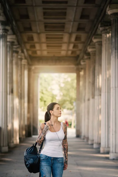 Joven mujer atractiva caminando bajo columnata en la Nationalga —  Fotos de Stock