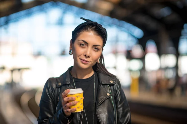 Χαμογελαστή νεαρή γυναίκα πορτρέτο με καφέ μέσα στο σταθμό του τρένου. B — Φωτογραφία Αρχείου