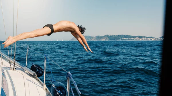 Yelkenli tekneden atlayan genç adam.