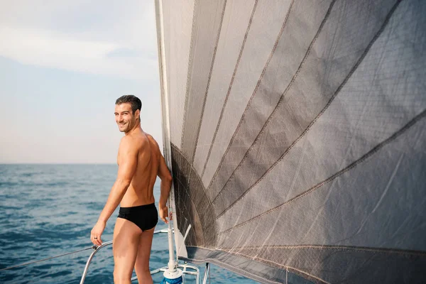 Yelkenli teknede gülümseyen genç adam portresi.
