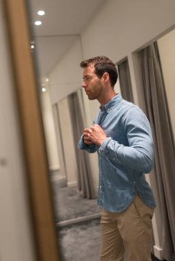 Elegant young man portrait while trying shirt in a clothing store.