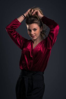 Confident beautiful woman studio portrait with long blonde hair wearing red dress. 