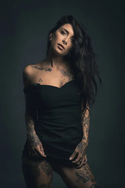 Sexy mujer estudio retrato con vestido negro y tatuajes contra — Foto de Stock