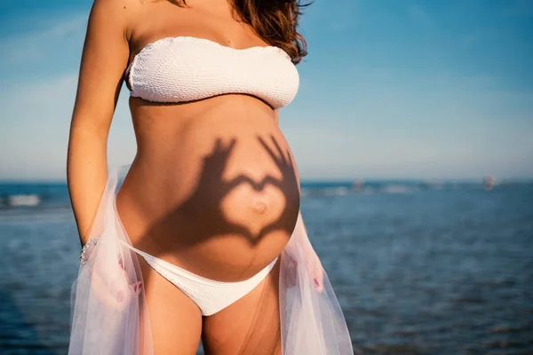年轻孕妇的肖像在夏天的海滩上 有着心形的影子 真实的生活方式形象 — 图库照片