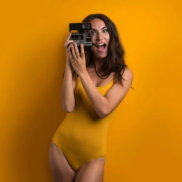カラフルな黄色の背景にヴィンテージカメラを保持美な笑顔の女性の肖像画 — ストック写真