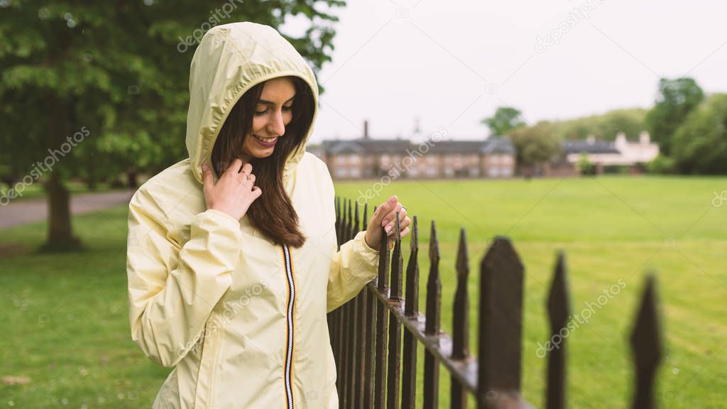 Young woman portrait wearing raincoat in a park in London.