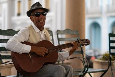 Cienfuegos, Küba - Mart, 2019: Sokakta geleneksel panama hasır şapka busking giyen gitar ile kıdemli adam şarkıcı.