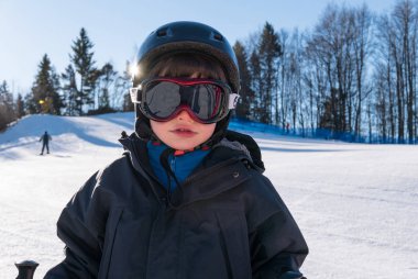 Küçük çocuk kar kayağında eğleniyor. Portreyi kapat.