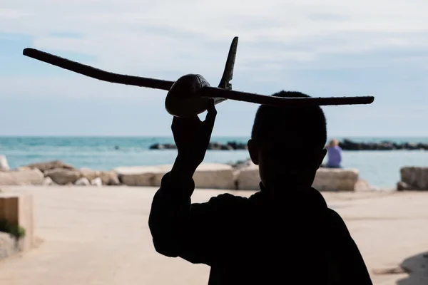 ビーチで空を背景にしたおもちゃの飛行機で遊んでいる子供のシルエット — ストック写真