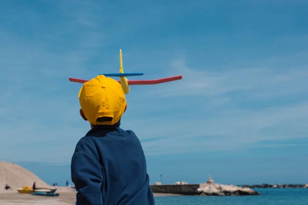 Happy kid playing with toy airplane against sky background on th — Stock Photo, Image