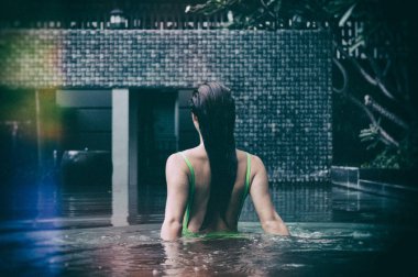 Yüzme havuzunda rahatlatıcı yeşil mayo giyen şehvetli güzel kadın portre