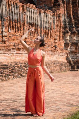 Genç kadın Ayutthaya, Tayland 'da geleneksel tapınağın önünde dans ediyor.