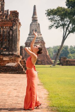 Genç kadın Ayutthaya, Tayland 'da geleneksel tapınağın önünde dans ediyor.