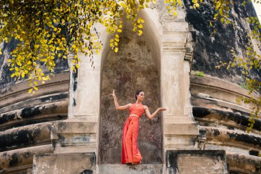 Genç kadın Ayutthaya, Tayland 'da geleneksel tapınağın önünde dans ediyor.