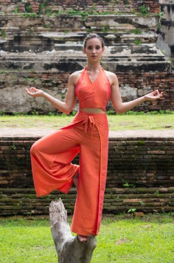 Genç kadın Ayutthaya, Tayland 'da geleneksel tapınağın önünde dans ediyor.