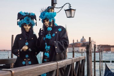 Sunset gökyüzü ile liman tarafından maskeler insanlar, Venedik Carnival, Italya