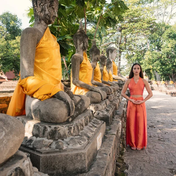 Junge Frau in traditioneller Kleidung neben traditionellem Buddha — Stockfoto