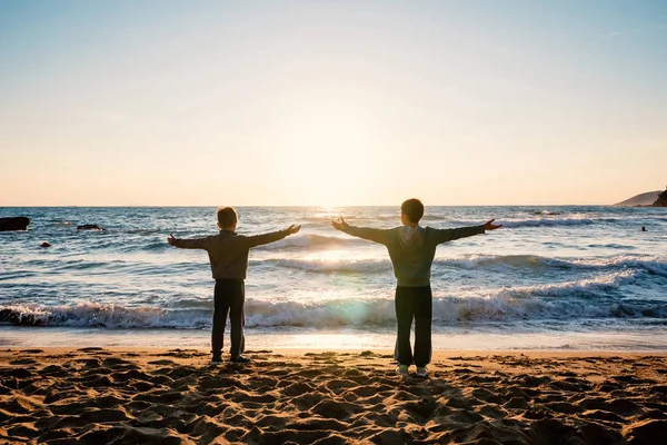 Retrato de silueta de hermanos jóvenes frente al mar al atardecer. —  Fotos de Stock