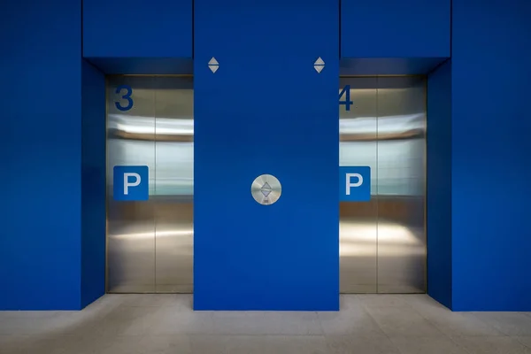 Modern elevators with closed steel doors inside business centre lobby.