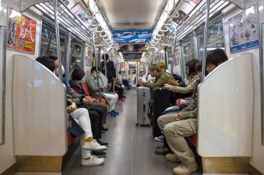Tokyo, Japonya - Mart, 2017: İnsanlar binerken metro vagonu içinde akıllı telefon kullanıyor. Modern toplumda iletişim eksikliği kavramı. 