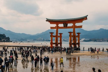 Hiroşima, Japonya - Circa Mart, 2017: Miyajima Adası'nda yüzen Torii kapısının altında yürüyen insanlar gelgit le. 