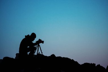 Profesyonel fotoğrafçının silueti gün ışığında fotoğraf çekiyor..