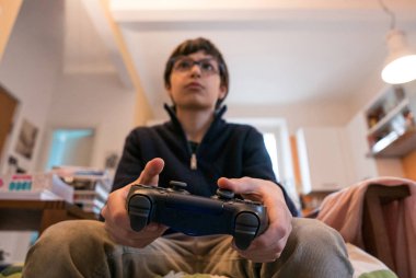 Video oyunlarında oynayan küçük bir çocuk elinde bir kumanda tutuyordu. Bulanık arkaplanı olan denetleyiciye odaklan.