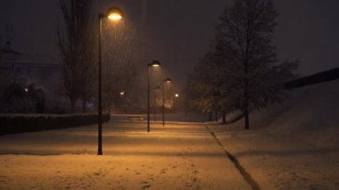 Gece sokakları, fener ışıkları ve parka düşen karlar.