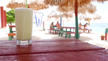 Deniz manzarası arka plan ve Küba bayrağı ile plajda bir bardak soğuk pina colada kokteyl. Küba.