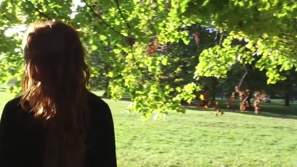 日当たりの良い公園で屋外を歩く若い女性 — ストック動画