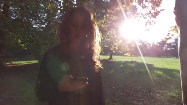 日当たりの良い公園で屋外を歩く若い女性 — ストック動画