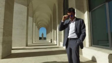 Roma, İtalya 'da yürüyen orta yaşlı bir işadamı. Arka plan olarak modern bina. 