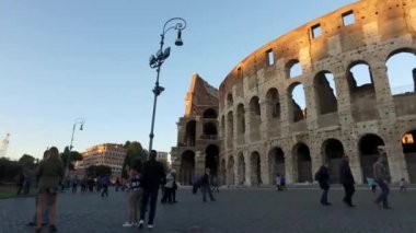 ROME, ITALY - CIRCA EKİBİ 2016: Roma İmparatorluğu 'nun sembolik bir sembolü olan Colosseum' un önünde yürüyen turistler. 2007 yılında Dünya 'nın yeni 7 harikası arasında yer aldı..