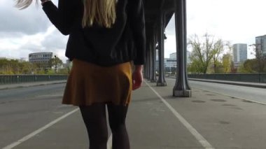 Paris, Fransa 'da Bir Hakeim köprüsünün altında yürürken kulaklıkla müzik dinleyen güzel sarışın kadın portresi..