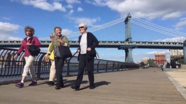 NEW YORK CITY - MAY 2015: People walking in Brooklyn Bridge Park in front of Manhattan Bridge. Brooklyn Bridge Park is an 85-acre (34 ha) park on the Brooklyn side of the East River in New York City.