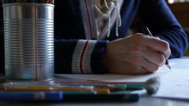 Close-up of woman drawing with pencil at home.
