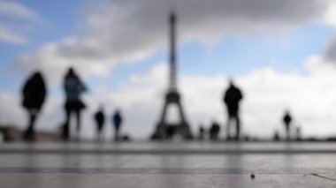 Eyfel Kulesi 'nin önünde mavi bulutlu gökyüzüne karşı yürüyen insanlar. Paris, Fransa.