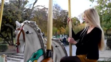 Young blonde woman smiling and having fun on the carousel in front of the Eiffel Tower in Paris, France.