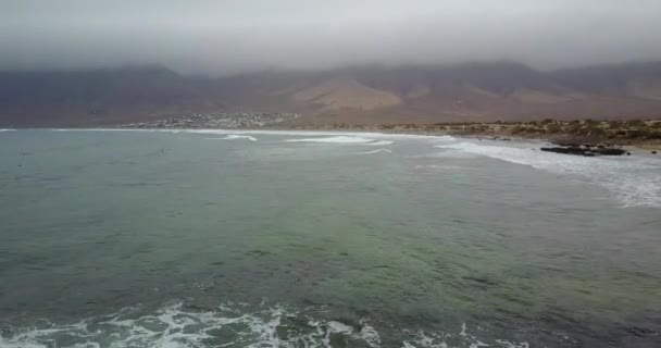 波涛滚滚的海滩与远处的山脉和多云的天空 — 图库视频影像
