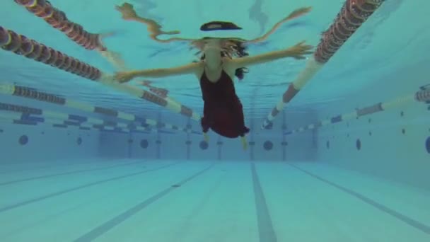 Підводна жінка з червоним платтям у басейні — стокове відео