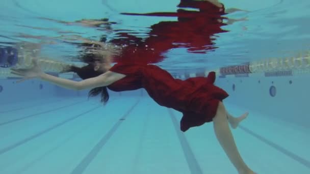 Mujer submarina con vestido rojo en la piscina — Vídeos de Stock