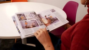 BOLOGNA, İTALYA - 2018: yeni evi için mobilya almadan önce IKEA kataloğu okuyan genç bir kadın. Ikea, hazır mobilya tasarlayan ve satan İsveçli çokuluslu bir gruptur..