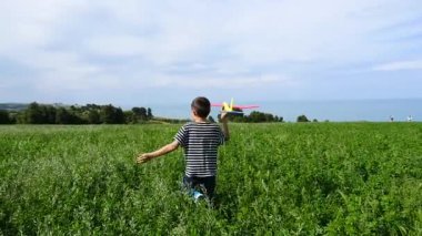 Mutlu çocuk kumsalda gökyüzüne karşı oyuncak uçakla oynuyor..