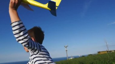 Mutlu çocuk kumsalda gökyüzüne karşı oyuncak uçakla oynuyor..