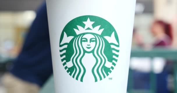 Кофейная Чашка Starbucks Логотипом Движущимися Людьми Заднем Плане — стоковое видео