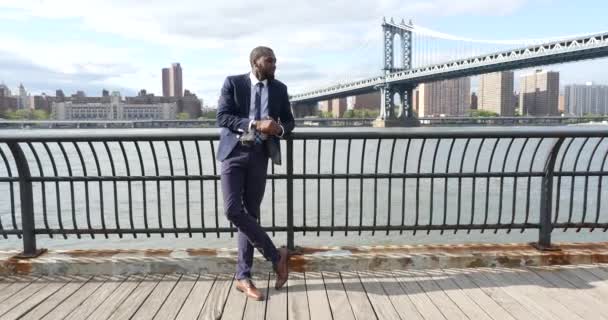 年轻自信的商人在纽约市布鲁克林曼哈顿大桥 Manhattan Bridge 的背景下装扮在码头上 — 图库视频影像