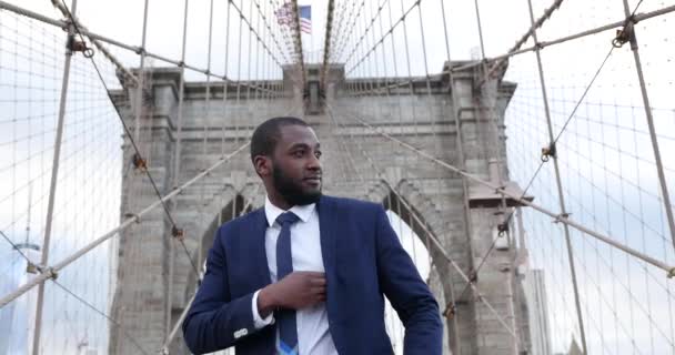 Mladý obchodník v obleku mluví na smartphonu v Brooklyn Bridge, New York City 